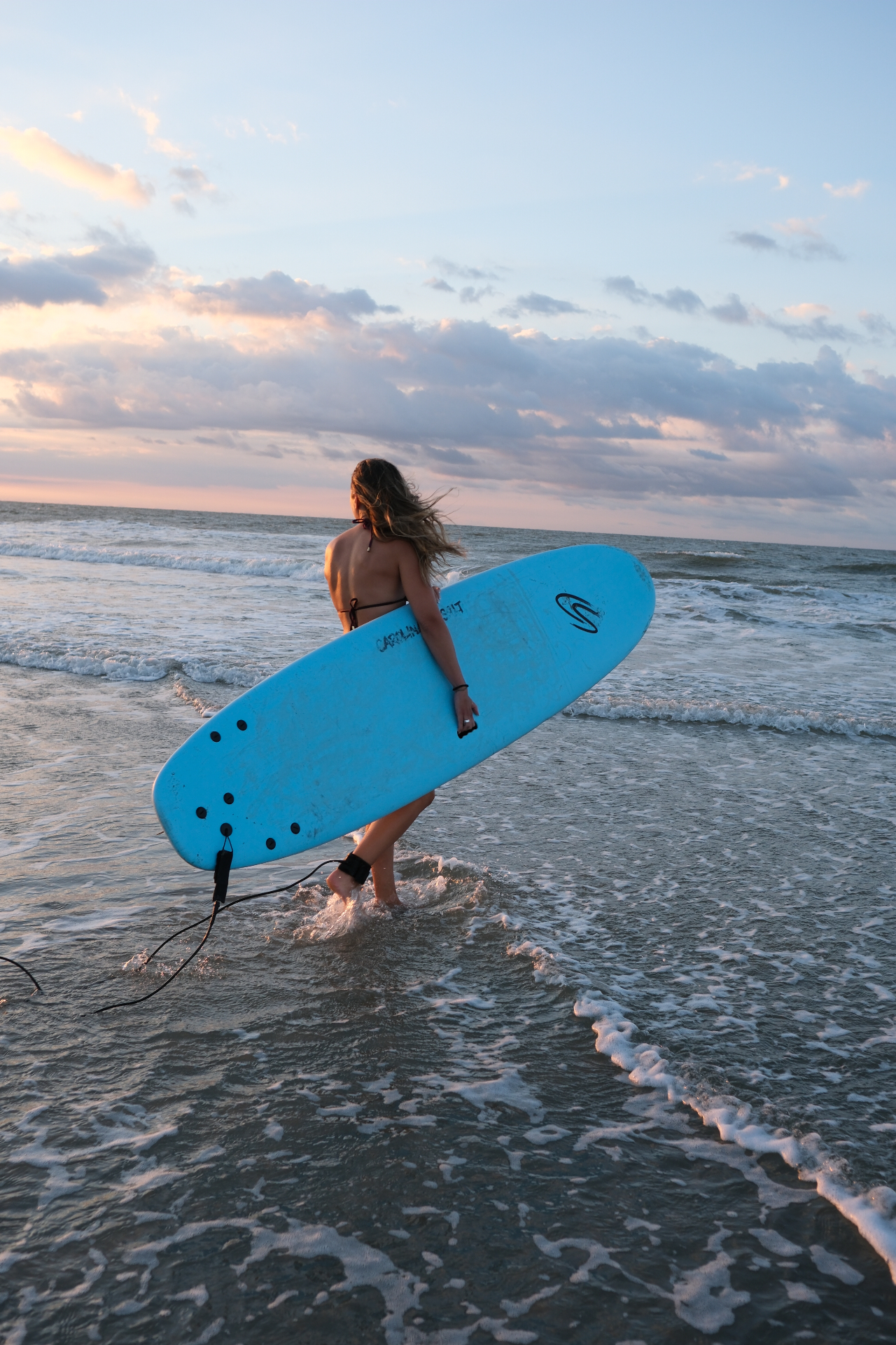 Surfer paddling out into the Atlantic at golden hour