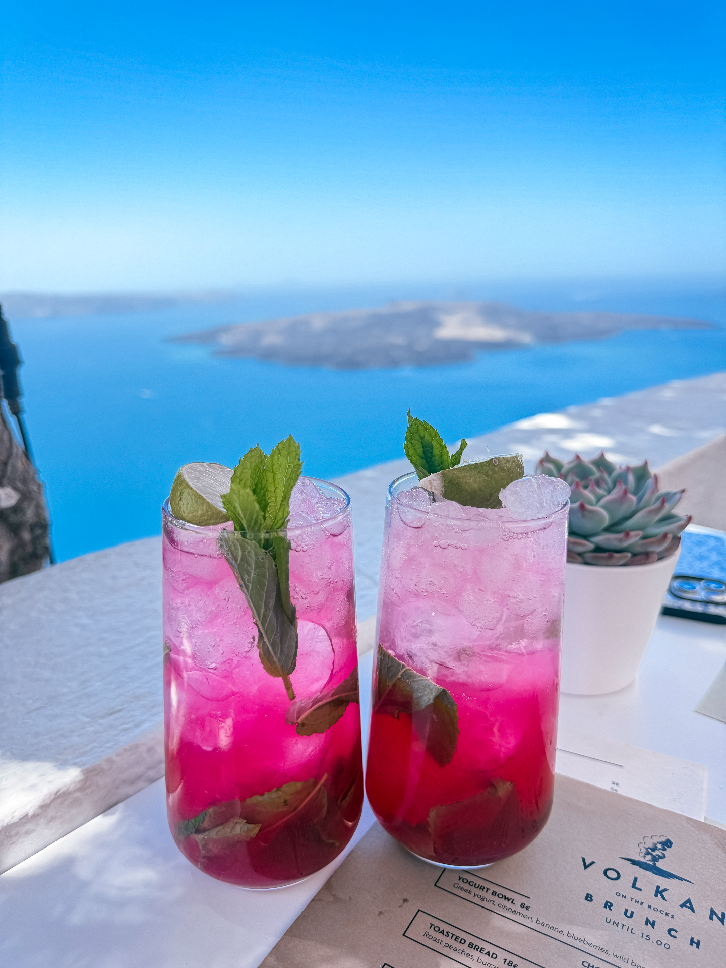 Two pink iced drinks garnished with lime and mint overlooking the Aegean Sea at Volkan Brunch, Santorini