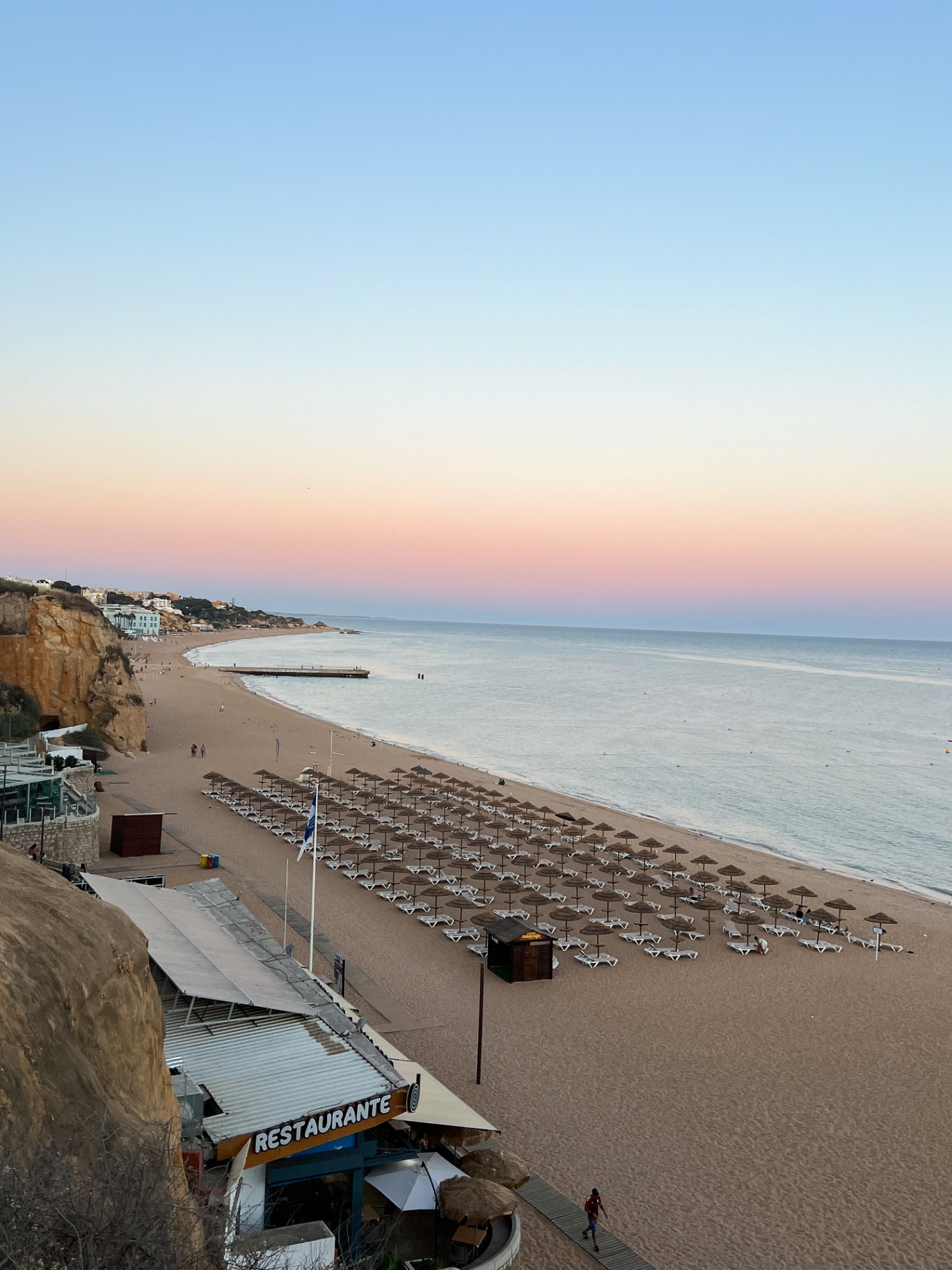 Pastel sunset over Algarve beach with rows of umbrellas