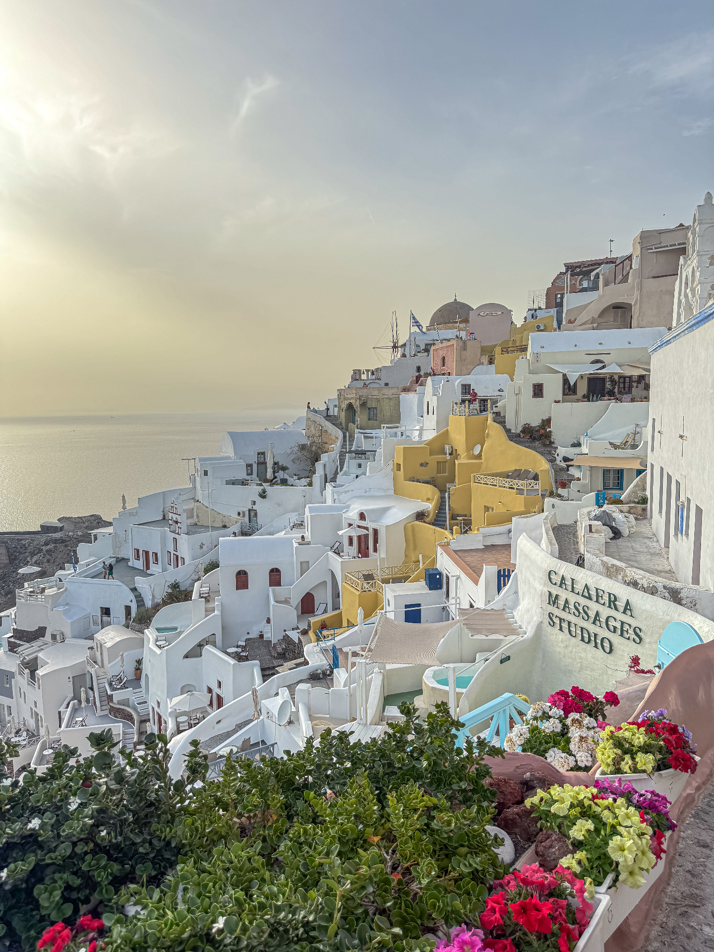 Golden hour over the white and yellow cliffside houses of Oia, Santorini