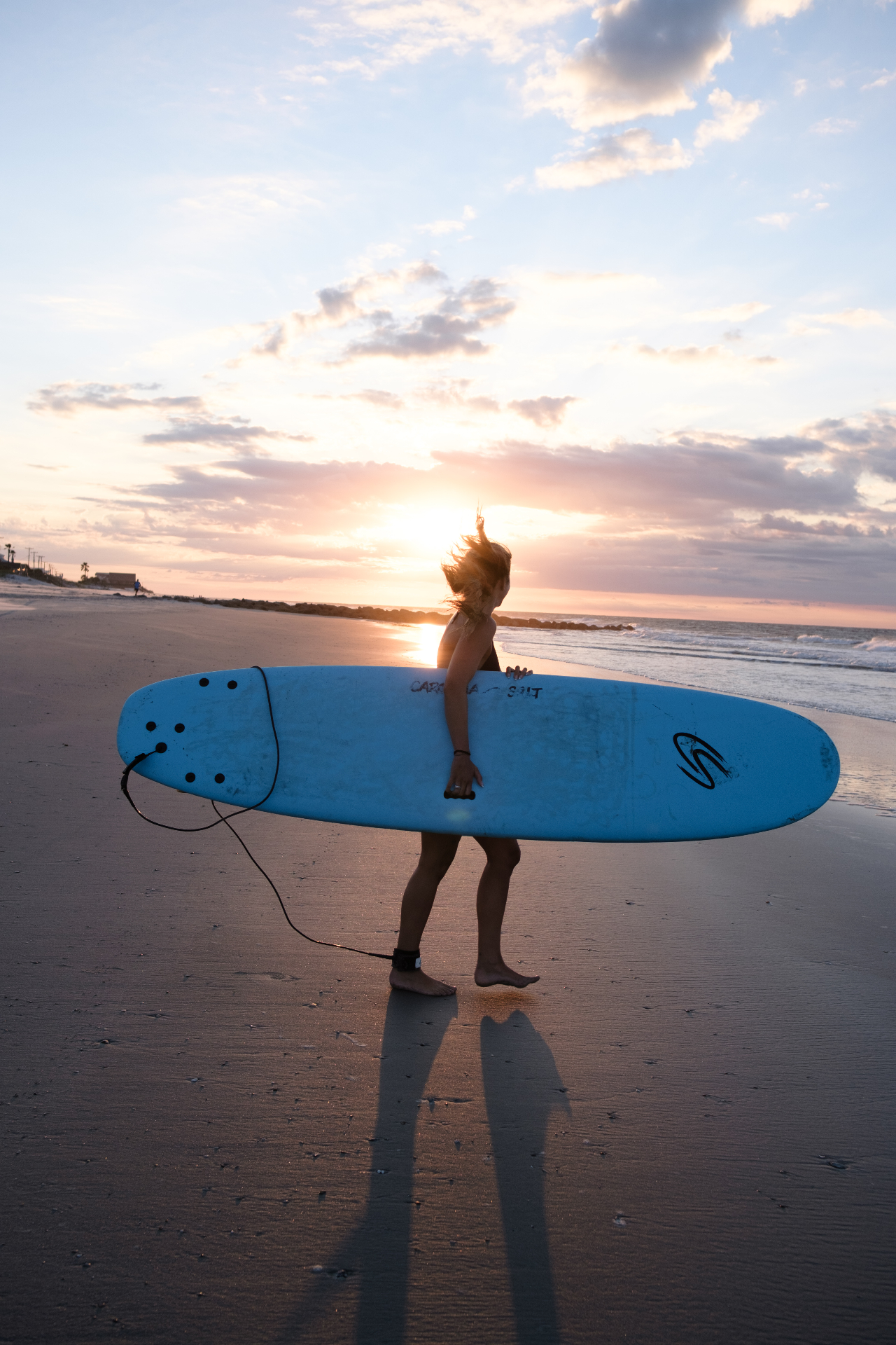 Surfer walking into the Atlantic at sunrise